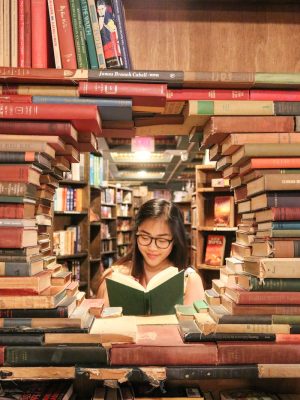 woman in green shirt sitting on books